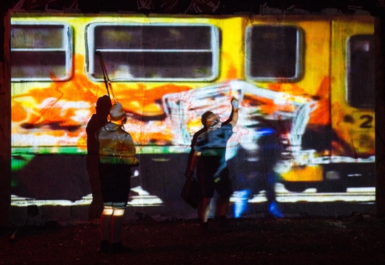 two artists trace a train and paint the train 