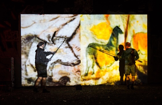 two artist paint live on a wall and trace cave paintings